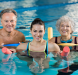 Three adults in a swimming pool with floating noodles